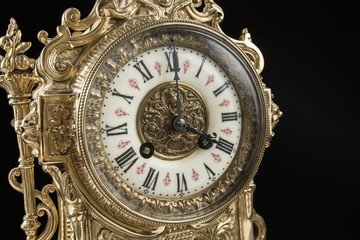 Fototapeta na wymiar dial of vintage bronze clock on black background, antique clock photo close up, old bronze clock in gilding, the fourth hours on the dial of antique clock