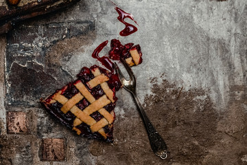 Flat-lay of cherry pie cut in slices over brown concrete background, top view. traditional seasonal...