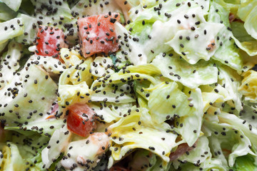 macro salad dressed with yogurt from onions tomatoes cucumbers iceberg lettuce sprinkled with Chia seeds . vegetable salad
