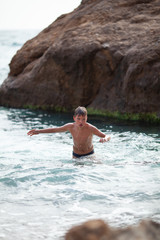 Happy beautiful teenager is swimming in the sea, a boy comes out of the water