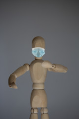 Statue of wood with a mouth and nose mask, as protection against viruses