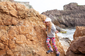 Happy pretty girl walks along the sea coast against the background of the sea, from behind a beautiful landscape