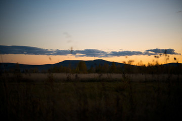 Evening landscape at sunset, warm sunlight over the field, Ural, September