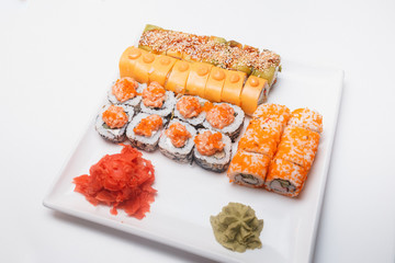 Sushi rolls set served on white plate, appetizing, big, Philadelphia, salmon, masago, orange, hot, sauce, kimchi, sesame, smoked, cucumber, ginger and wasabi