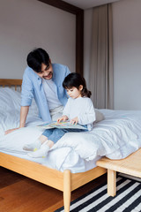 Fototapeta premium A pair of father and daughter reading in bed