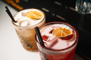 Two Red and Yellow ice cocktails in a glass served with dried orange fruit 