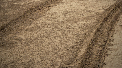 Tire prints on beach sand left by off-road vehicle. Abstract background and pattern.