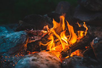 Vivid smoldered firewoods burned in fire close-up. Atmospheric warm background with orange flame of...