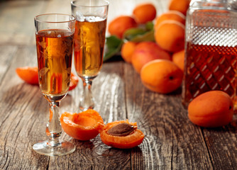 Apricot liquor and fresh apricots on a old wooden table.