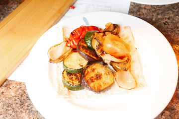 A bowl of spicy  grilled vegetables snack served on pita bread. Healthy salad