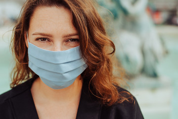 Close up portrait of a millennial caucasian woman wearing a protective mask, looking at camera, during pandemic of coronavirus in Portugal. New normal or stay safe concept
