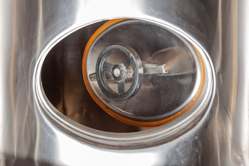 Brewery, open hatch in a beer tank, cylinder-conical fermentation tank in drops of water