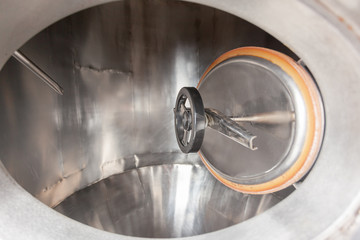 Brewery, open hatch in a beer tank, cylinder-conical fermentation tank in drops of water