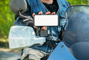 Motor biker is showing in hands a blank screen mobile phone. Online navigator.