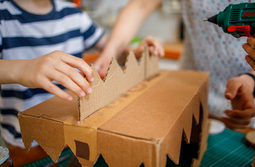 Mom and kids making a cardboard dinosaur costume	
