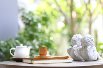 White tea kettle and brown wooden  cup with notebook on wooden table outdoor view