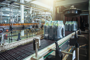 Conveyor belt or line with packaged juice bottles and ready to delivery or shipment on beverage factory equipment machinery.