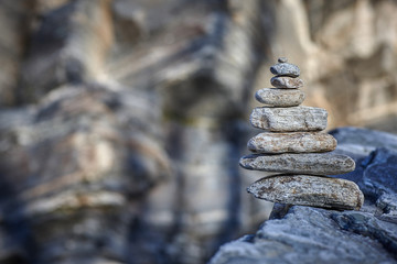 pyramid of various shapes of stones against a stone wall