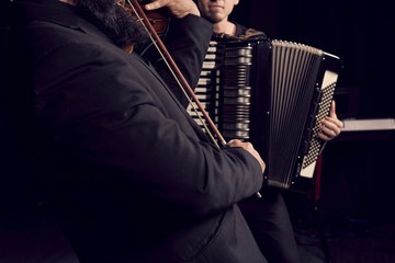 Detail of hands playing an accordion instrument and a violin