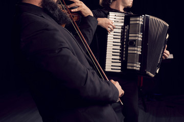 Detail of hands playing an accordion instrument and a violin © Diego