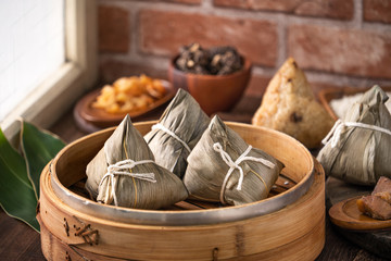Zongzi - Chinese rice dumpling zongzi in a steamer on wooden table with red brick, window background at home for Dragon Boat Festival concept, close up.