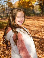 Autumn portrait of adorable smiling little girl child preteen having fun in the park