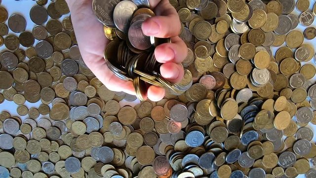 Girl picks up handful of coins in her hand and throws it over coins on table