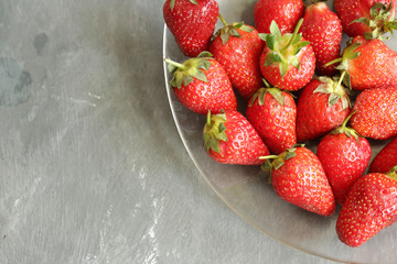 on a gray background plate with strawberries, ripe berry
