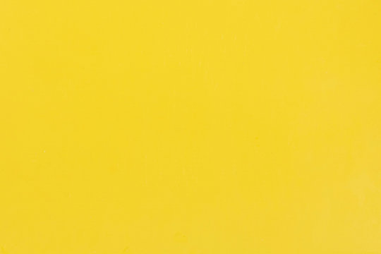 Clean bright yellow background with simple surface. High resolution photo. Color plastic with scratches, empty space.