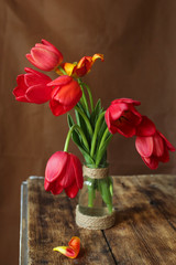 on a wooden background red tulips in a vase
