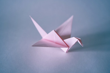 Pink paper dragon figurine stands on a white background.