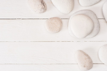 Top view of sea stones on white wooden surface with copy space