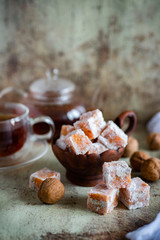 Orange Turkish delight in a clay bowl on a gray background. Vertical photo