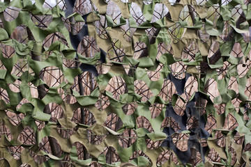 Military camouflage net on the fence