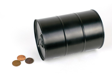 concept of falling oil prices a black iron barrel lies on its side next to it are scattered small coins on the white background