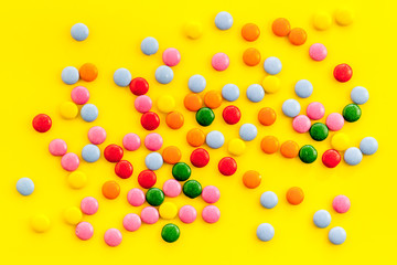 Color candy on yellow background top view