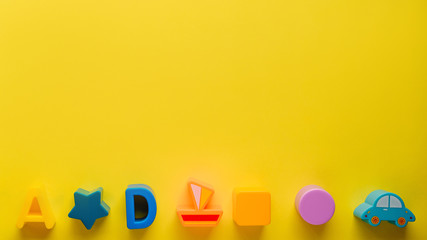 Top view on children s toys on a yellow background. Children's toys on the table. concept for advertising toys for children. Copy space children's toy.