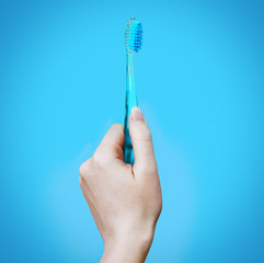 Female hand holds a blue toothbrush