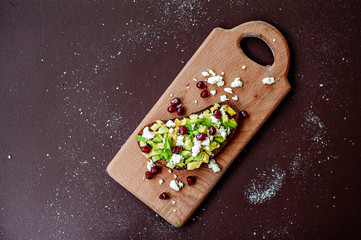 Sandwich with avocado, cottage cheese and pomegranate seeds on cutting board on table close up. Healthy food concept. Selective focus.