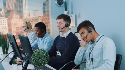 Bored and dissatisfied black call center agent talking to the client on phone. He is behaving...