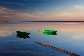A calm dawn on a lake with boats in the water