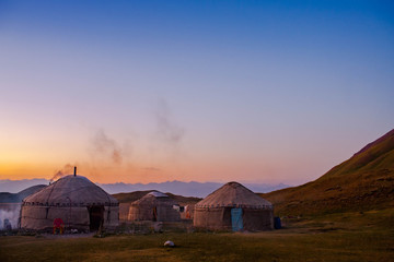 Traditional village in Central Asia. Nomadic lifestyle. Yurts. Scenic landcape of sunset in mountainious area.