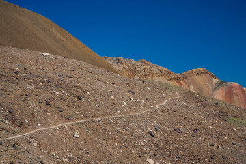 Scenic landscape of mountainious terrain. Sand and stones on the slope of the mountain. Blue sky.