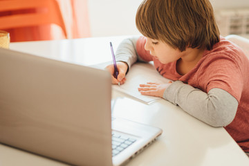 Boy studying online watching his lesson on laptop. Studying home