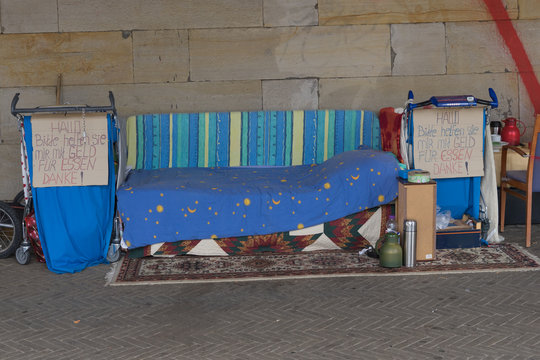 Schlafplatz mit in Einkaufswägen zusammengetragenem Hab und Gut eines Obdachlosen auf der Strasse unter einer Brücke