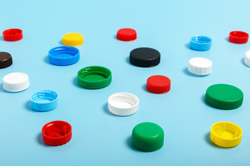  Multi-colored plastic bottle caps on a blue background. The problem of environmental pollution. Pattern. Recycling plastic.