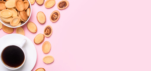 Homemade Russian nuts with condensed milk on a light pink background, wafer napkin. Cut nuts with condensed milk. Bitten goodies for coffee.