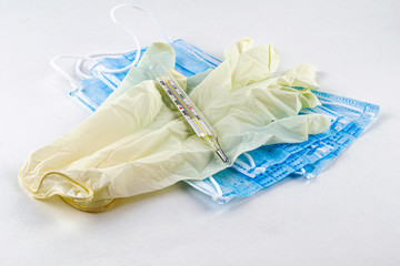 medical hygiene protective masks, rubber gloves and thermometer on the white background
