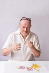 Portrait of an old man, 60-65 years old. Coronavirus hazard concept for the elderly. A man is taking medicine.