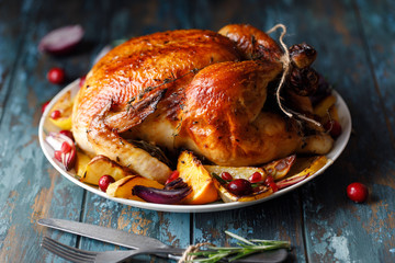 Roast whole chicken with roast vegetables on plate on a table